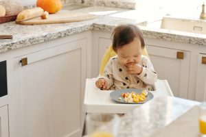 Baby seated, happily eating baby food.