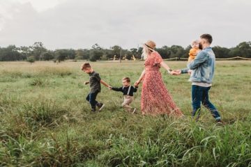 Happy family of five walking through the field.