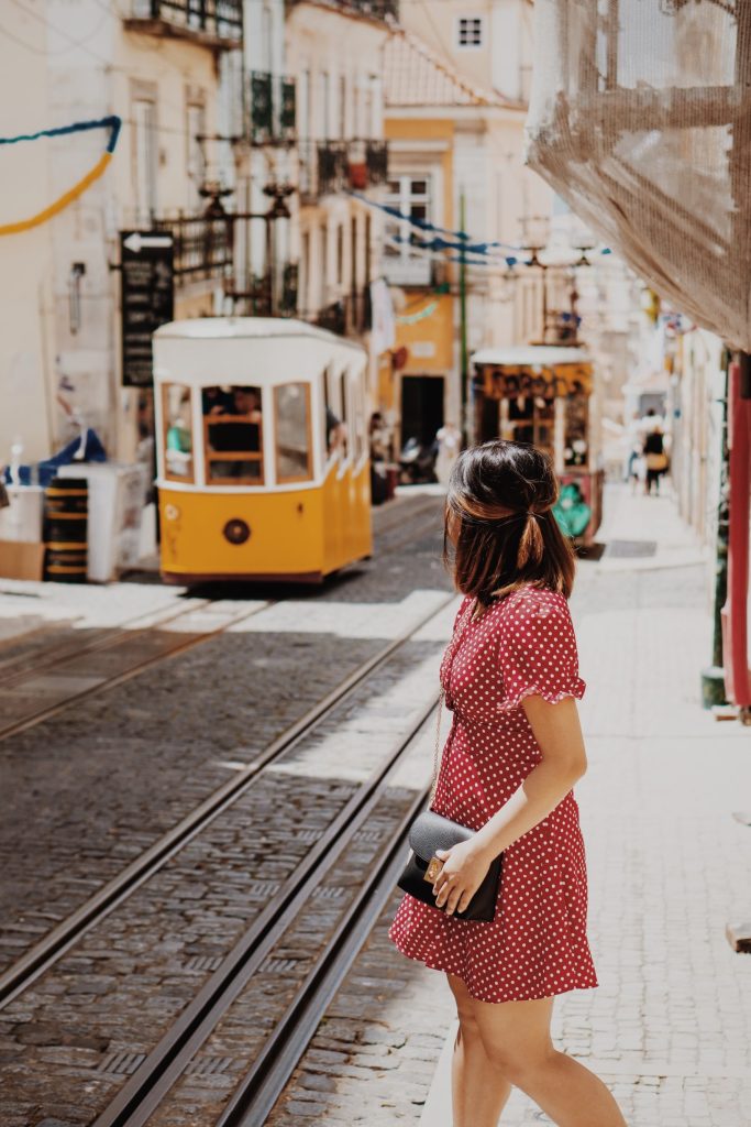 Historic cobblestone street lined with colorful buildings, as a woman traveler strolls through the charming European city.